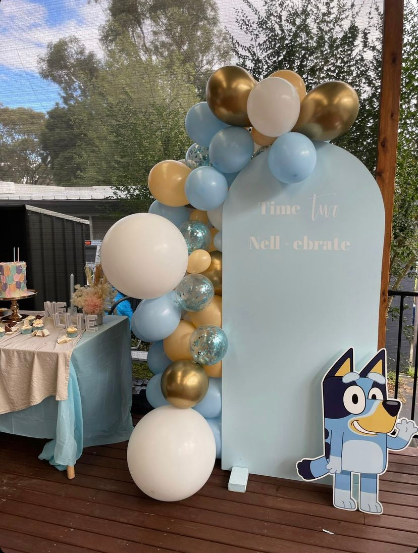 Decorative setup with balloons, a sign, and a cutout of Bluey on a wooden deck.