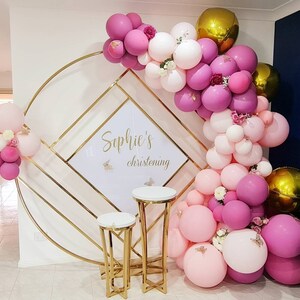 Decorative balloon arch with 'Sophie's christening' sign in a room.