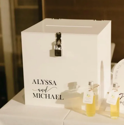 White box with 'Alyssa and Michael' text, lock, and bottles on a table.