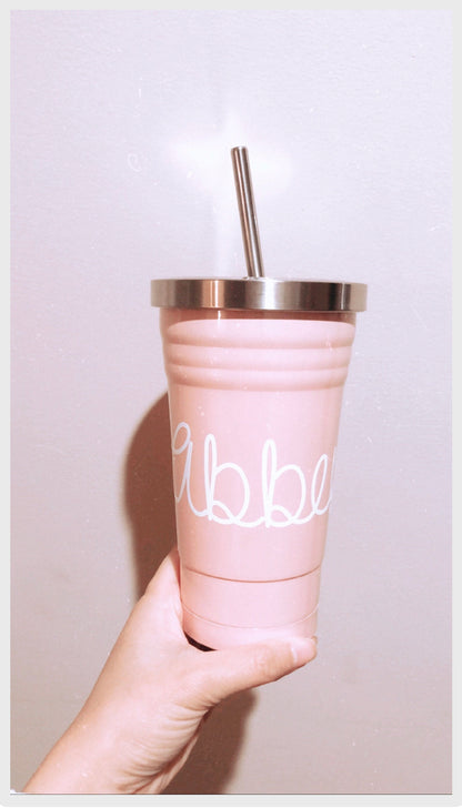 Pink tumbler with silver lid and straw held by a hand against a light background